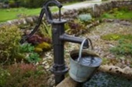 A bucket of water is pouring from an old fashioned well.