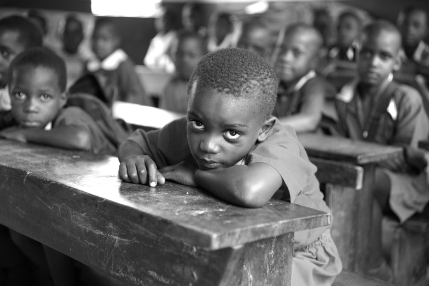 A black and white photo of a boy in front of some other people.