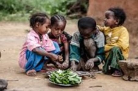 A group of children sitting around a bowl of food.
