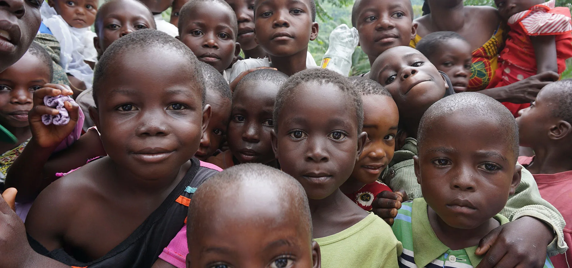 A group of children standing together in front of trees.