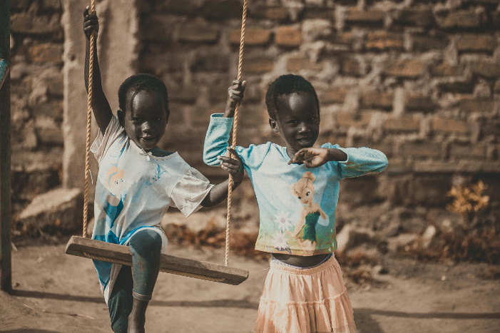 Two children are swinging on a swing.